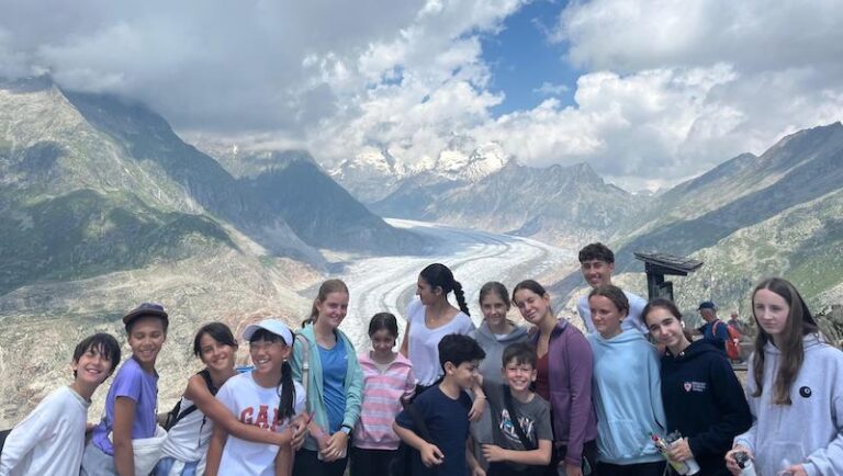 Summer camp group photo in front of a glacier in the Swiss Alps