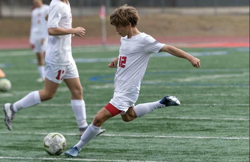 Young football player striking the ball on an artificial pitch