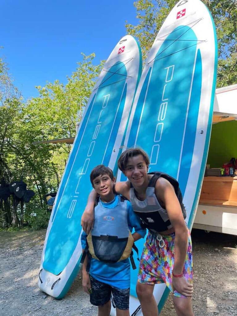 Two summer camp participants in front of paddle boards